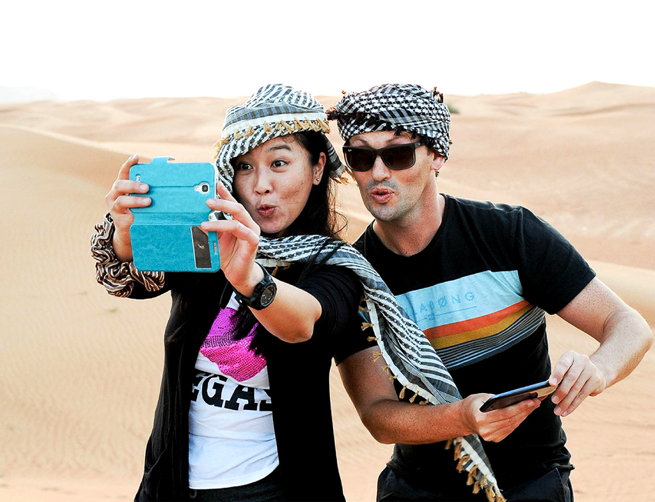 Two delegates donned in Emirati style Arab headgear, taking a selfie during a desert safari tour in Dubai